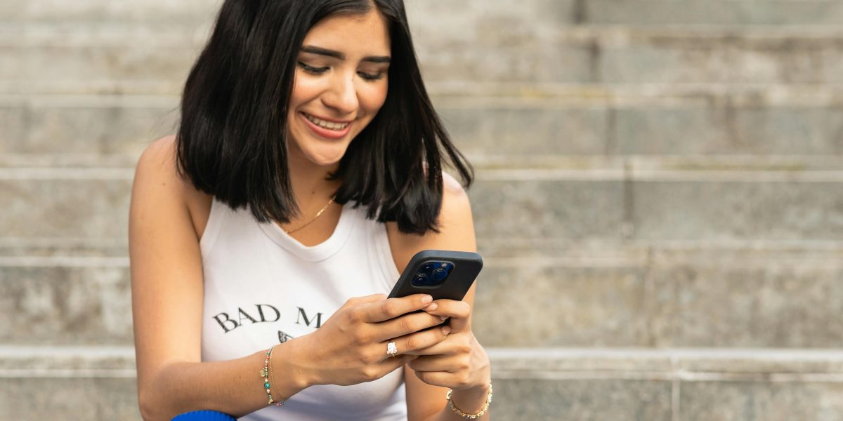 A person joyfully laughing while looking at content on their smartphone.