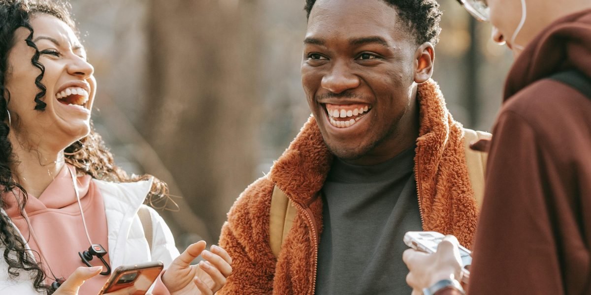 Friends laughing together while looking at something funny on a smartphone, sharing a humorous moment.